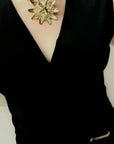 Black top with a passion flower necklace featuring a large, intricate flower pendant.