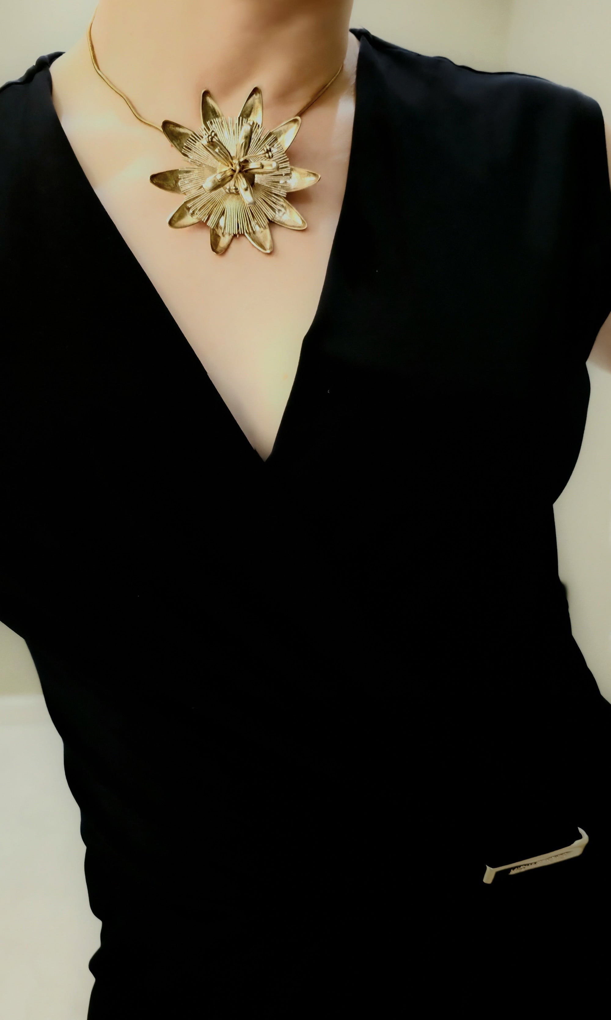 Black top with a passion flower necklace featuring a large, intricate flower pendant.